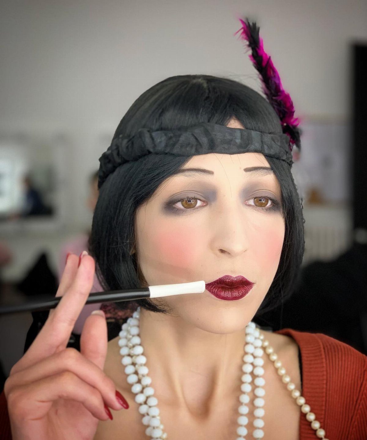 1920s Women Makeup: 9 Ideas for Lips, Eyes and Nails 3 Woman with 1920s makeup and flapper accessories applying red lipstick with a brush