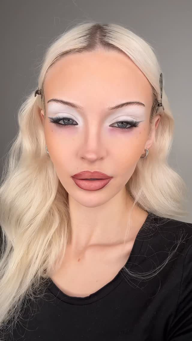 2006 Makeup Look Ideas: 6 Styles From Frosted Shadow to Glitter 2 Woman with thin eyebrows, white eyeshadow, and matte lips posing against grey background