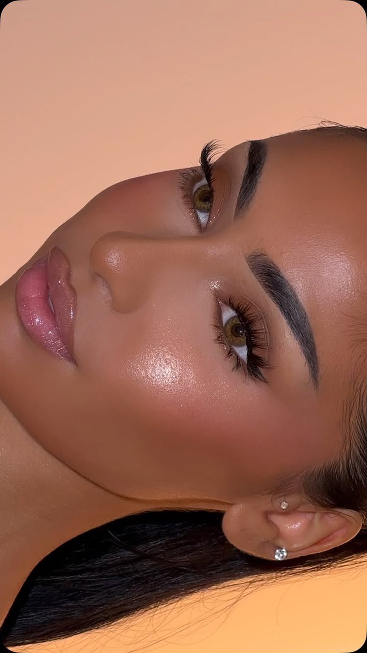 Woman with glossy nude lips, defined brows, and voluminous lashes posing for a portrait.
