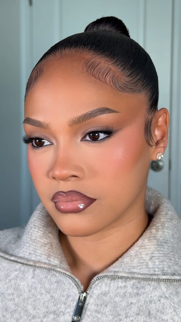 Woman with full glam makeup featuring peach blush and glossy nude lips.
