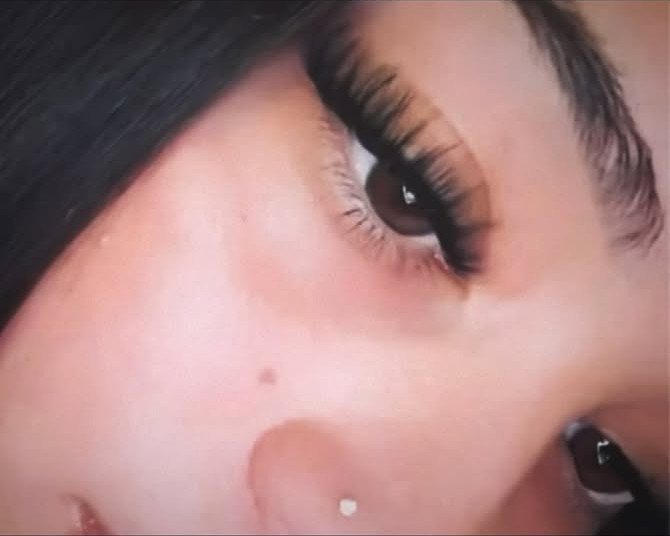 Close-up of an eye with long, voluminous black eyelashes and defined brows.