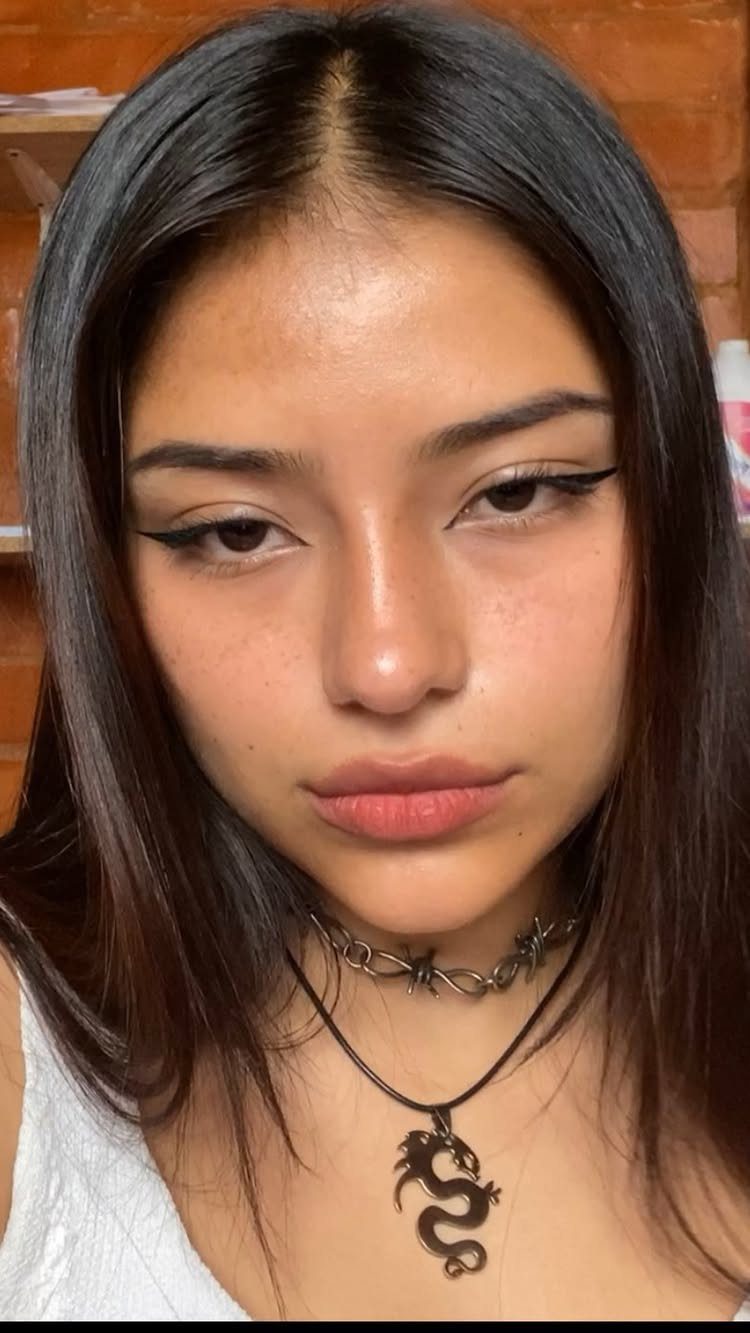 Young woman with sharp winged black eyeliner and a dragon pendant necklace.