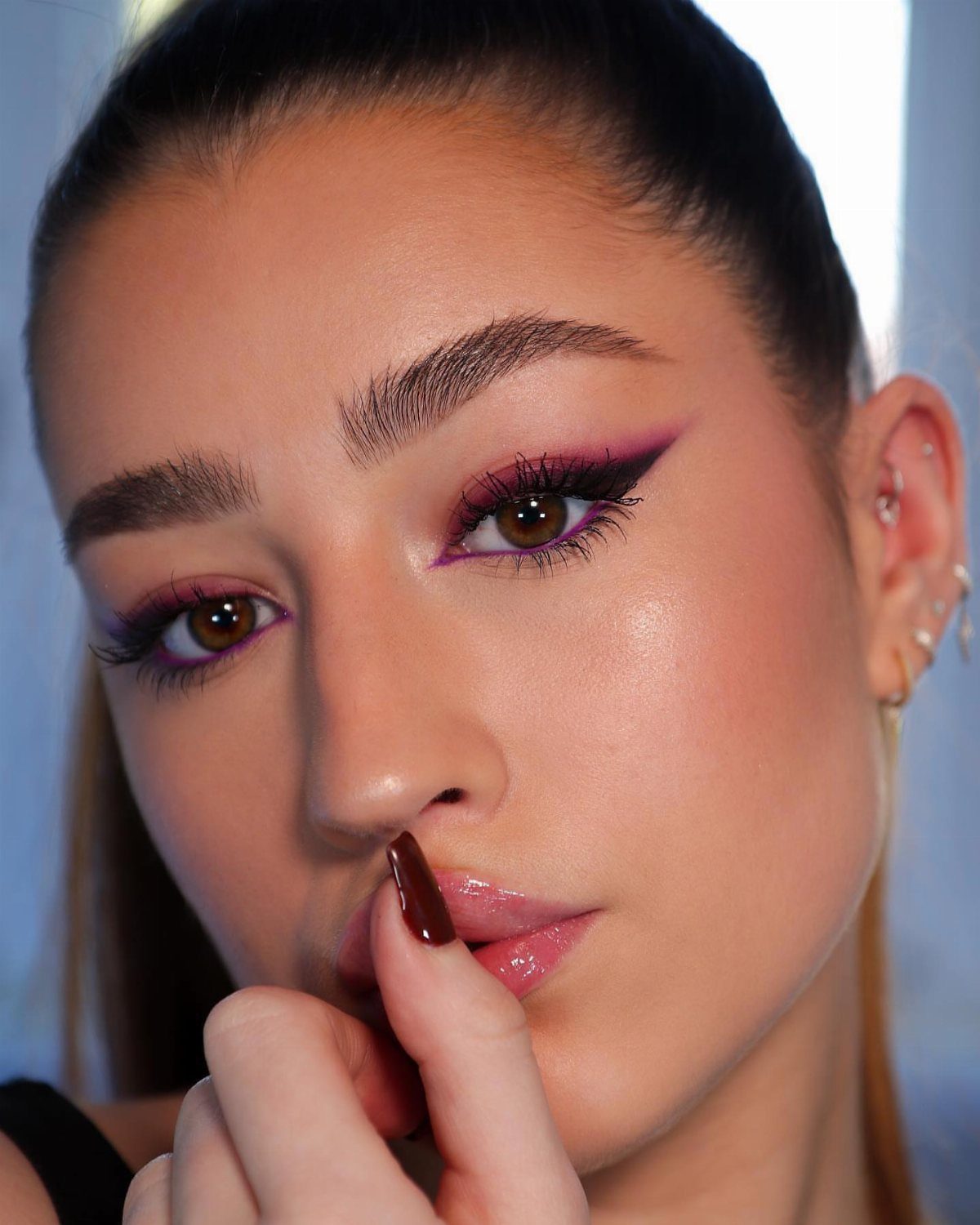 Black Purple Makeup Ideas: 5 Looks for Eyes and Lips 1 Woman with purple and black eyeshadow and sharp black winged eyeliner posing.