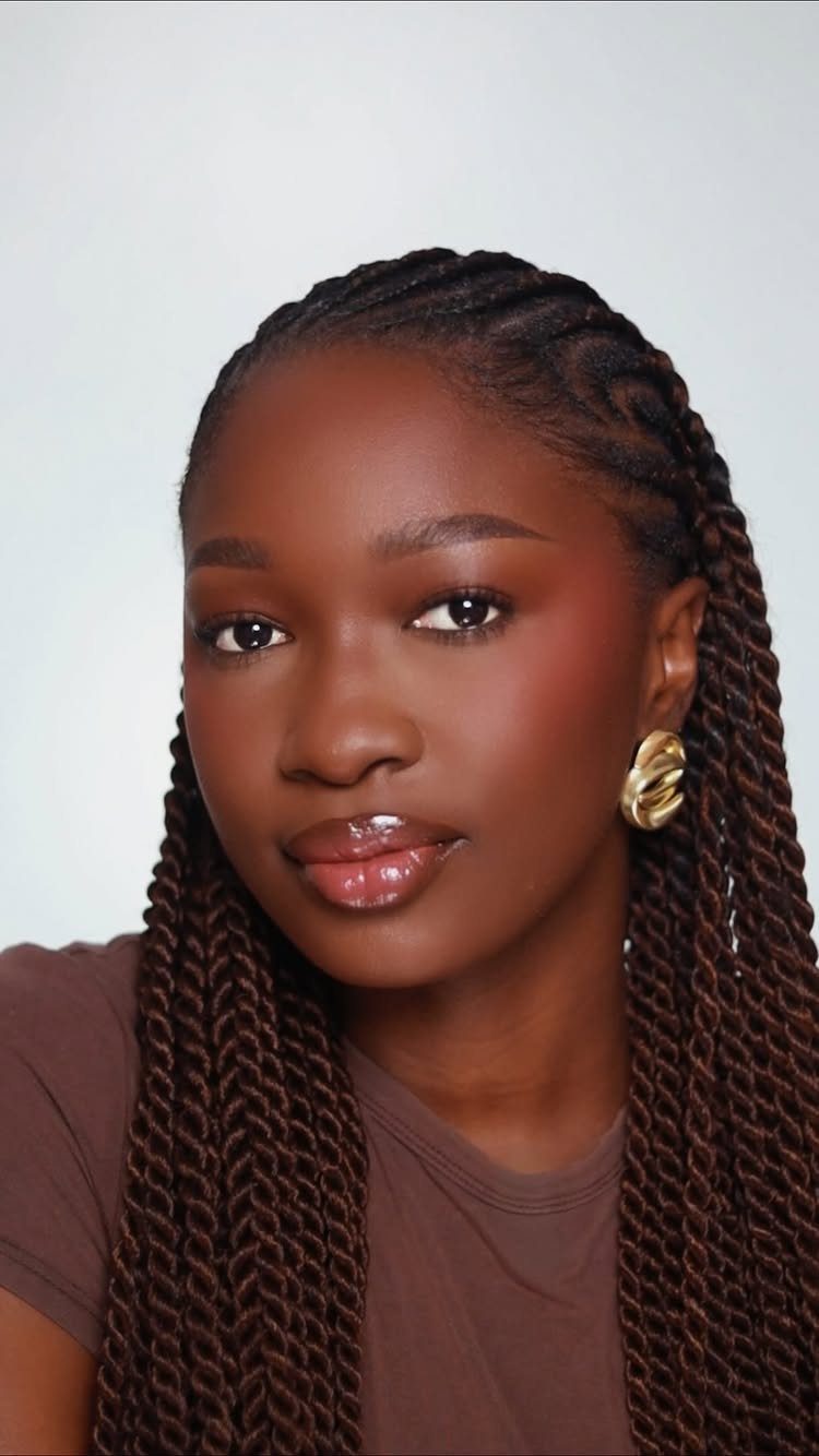 Black Skin Makeup Ideas: 8 Looks From Bronzer to Glossy Lips 4 Black woman with glowing dewy foundation, glossy lips, and long brown braids.