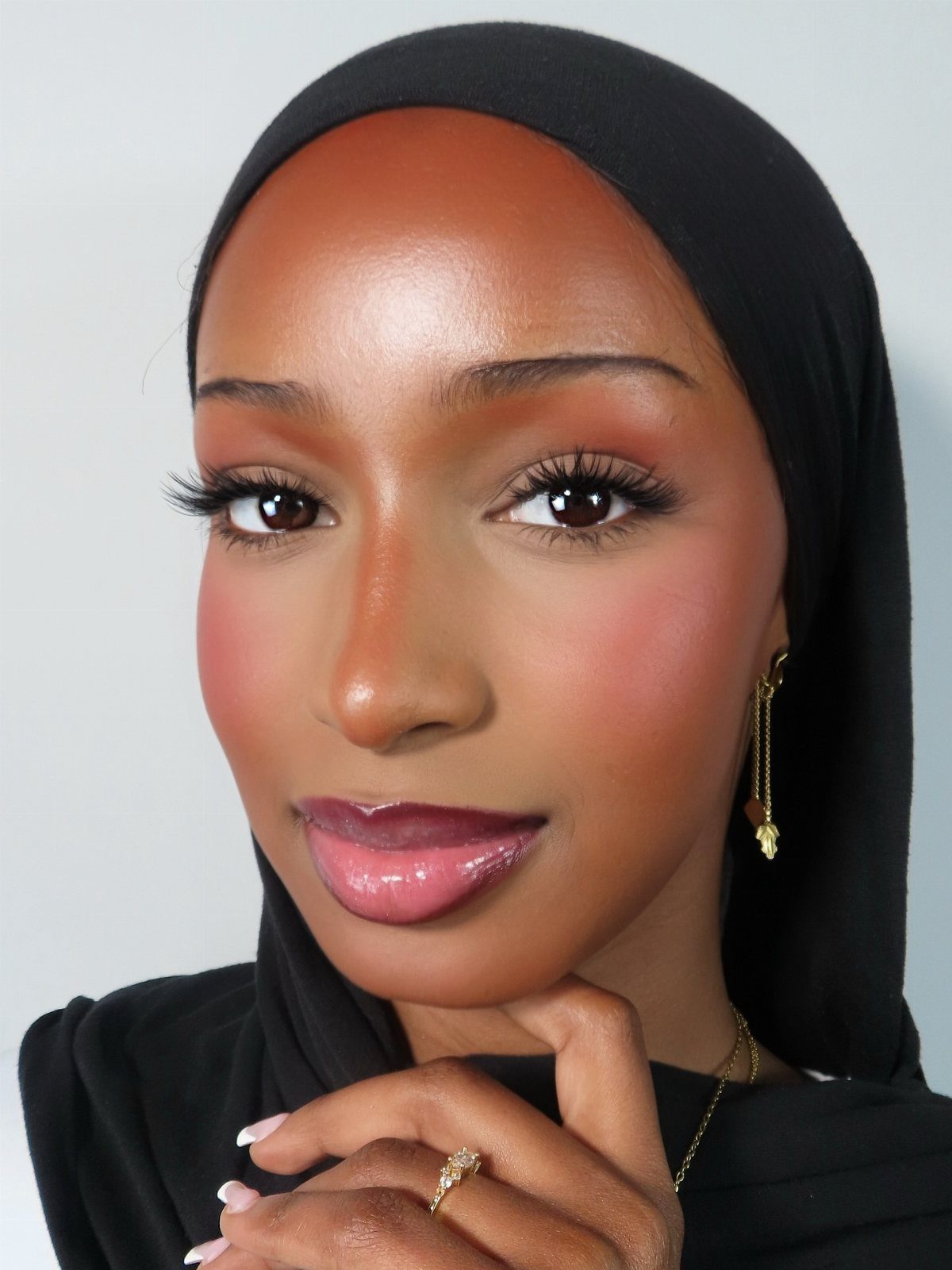 Black Skin Makeup Ideas: 8 Looks From Bronzer to Glossy Lips 2 Woman with dark skin wearing a black hijab and long false eyelashes.