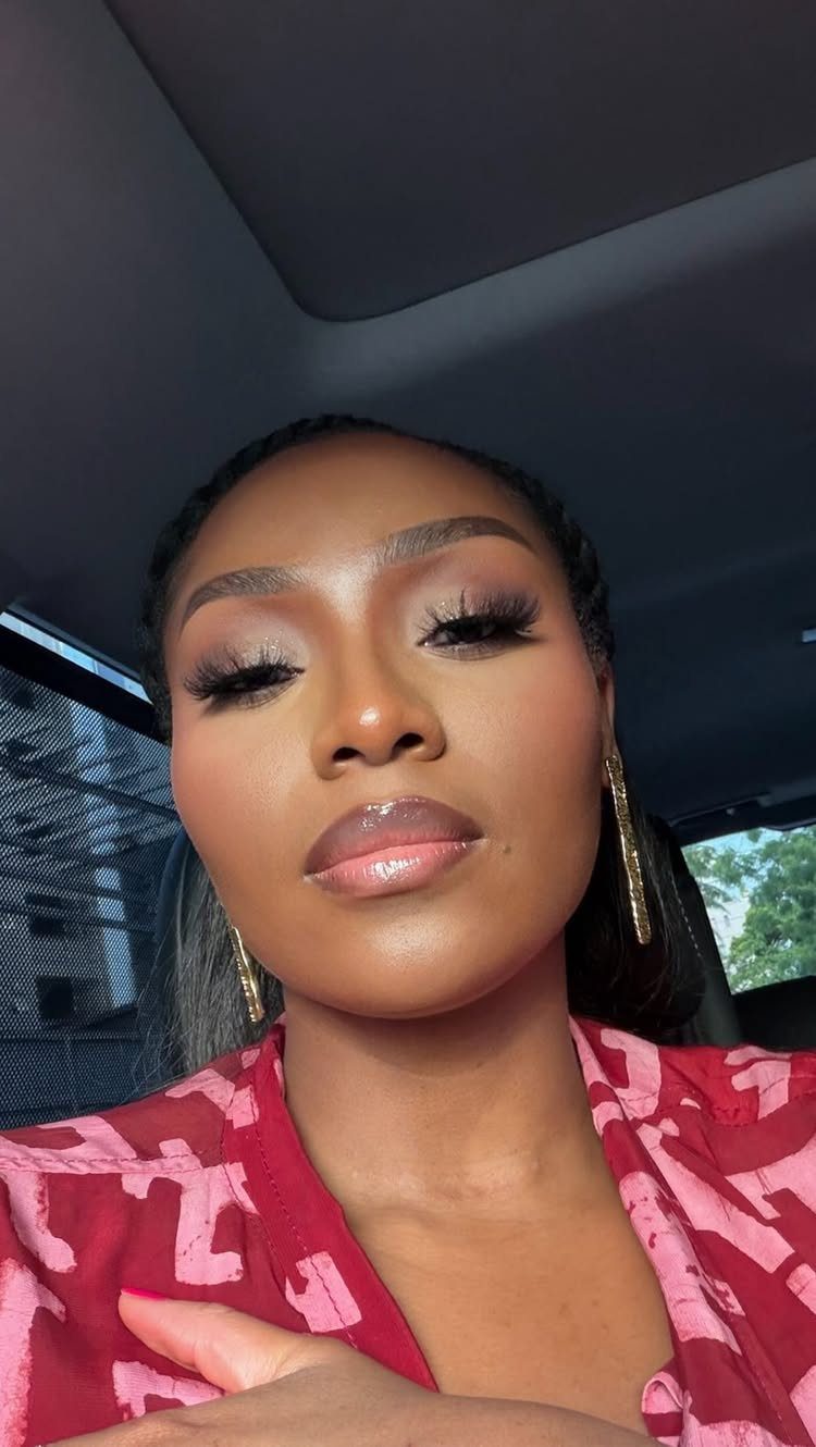 Black Skin Makeup Ideas: 8 Looks From Bronzer to Glossy Lips 6 Black woman with full makeup and glossy lips posing in a car.