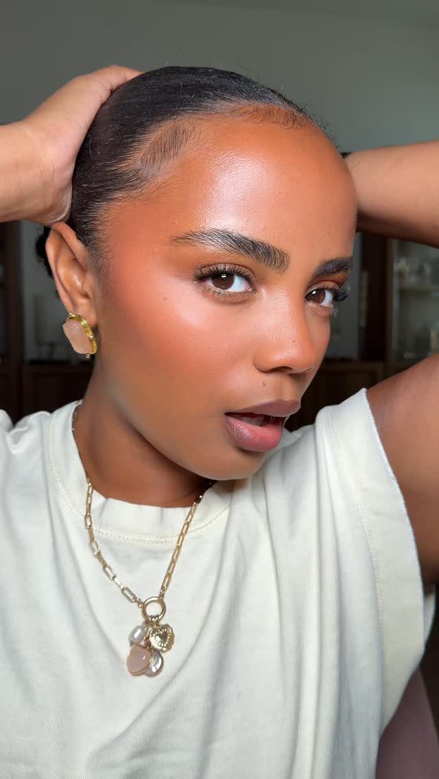 Black Skin Makeup Ideas: 8 Looks From Bronzer to Glossy Lips 1 Black woman with glowing highlighter on her cheekbones and forehead posing for portrait