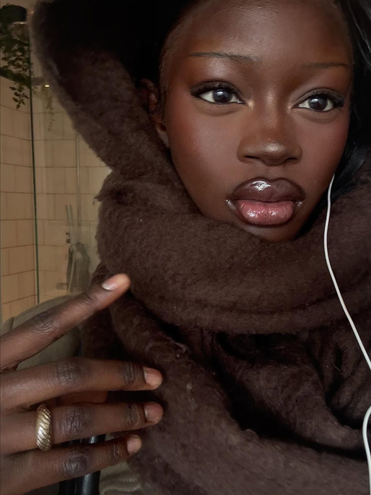 Black Skin Makeup Ideas: 8 Looks From Bronzer to Glossy Lips 8 Woman with dark skin wearing a brown fuzzy scarf and natural glossy makeup.