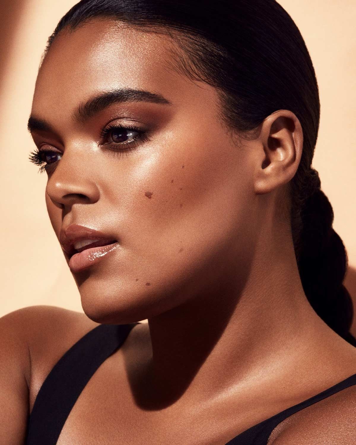 Black Skin Makeup Ideas: 8 Looks From Bronzer to Glossy Lips 3 Black woman with glowing skin wearing warm bronzer and glossy lip makeup.