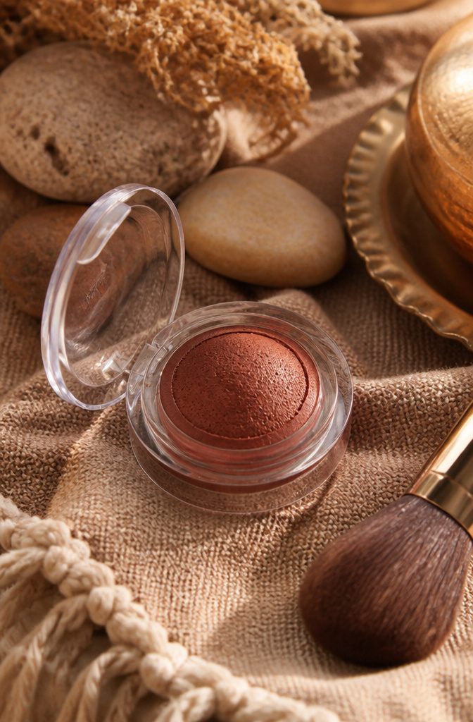 MAC Glow Play Cushiony Blush in a decorative setting with textiles.