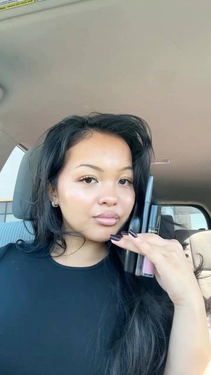 Woman with glowing skin and neutral makeup posing inside a car.