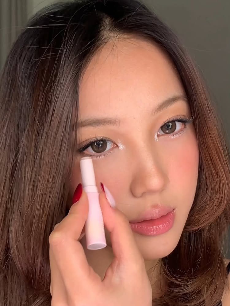 Daily Smokey Eye Ideas: 9 Looks for Every Day 3 Woman with shimmery white eyeshadow in inner corners holding a pink makeup applicator