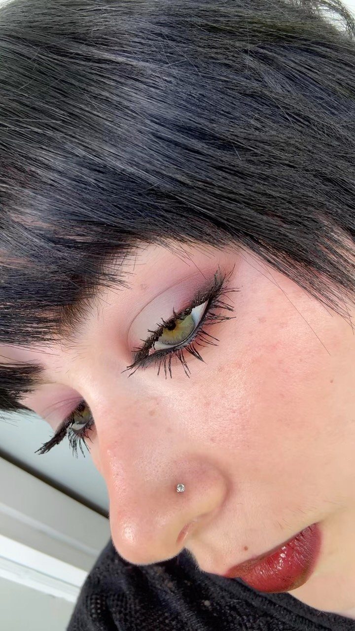 Person with black hair wearing heavy black mascara and thick winged eyeliner.