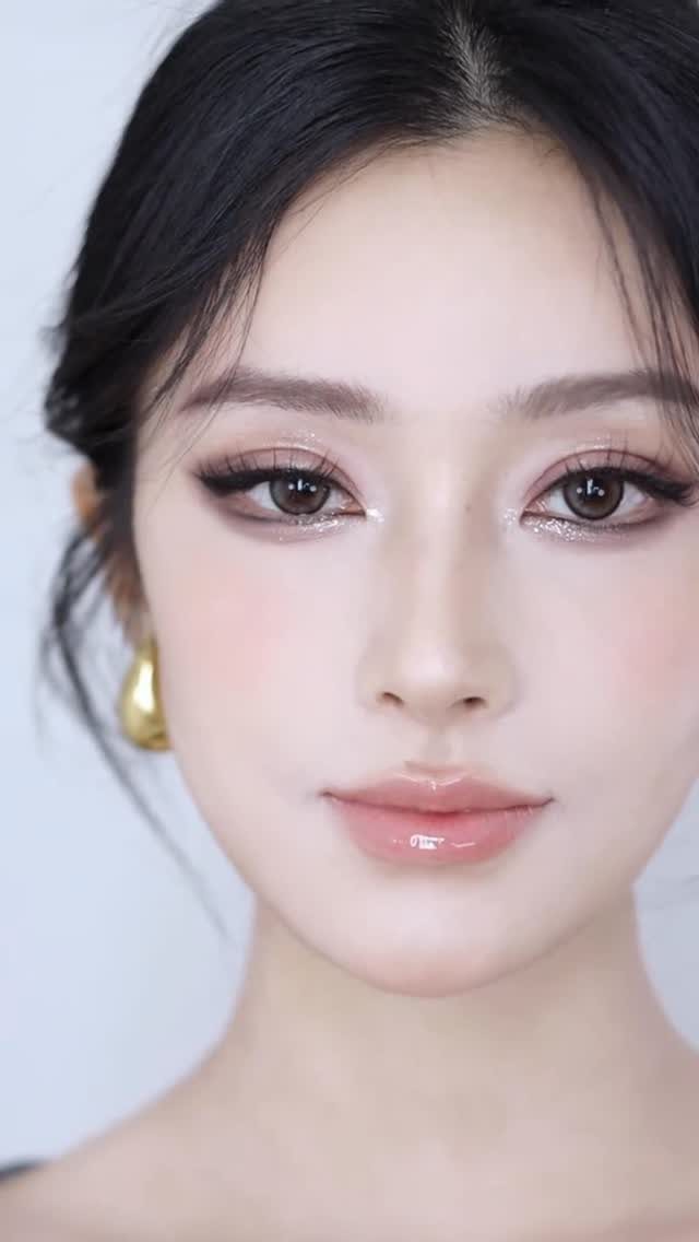 Woman with dewy skin, glossy pink lips, and shimmering natural makeup look.