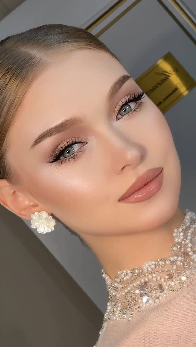 Woman with soft glam makeup, neutral tones, and a beaded pearl necklace.