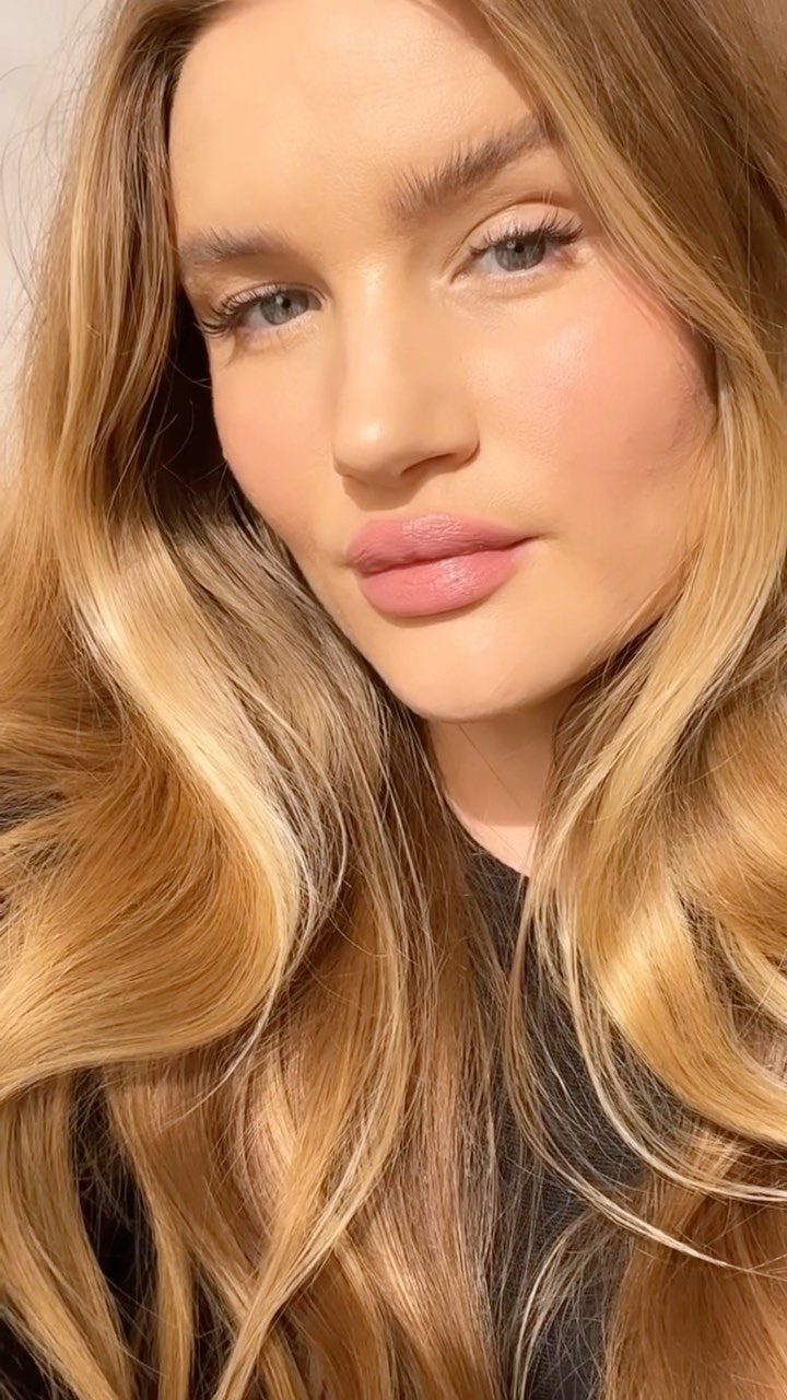 Woman with blonde wavy hair wearing soft rosy blush and pink lipstick.