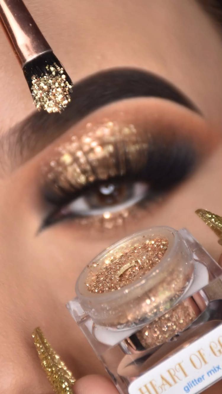 Eye with gold glitter eyeshadow, winged eyeliner, and a glitter makeup jar.