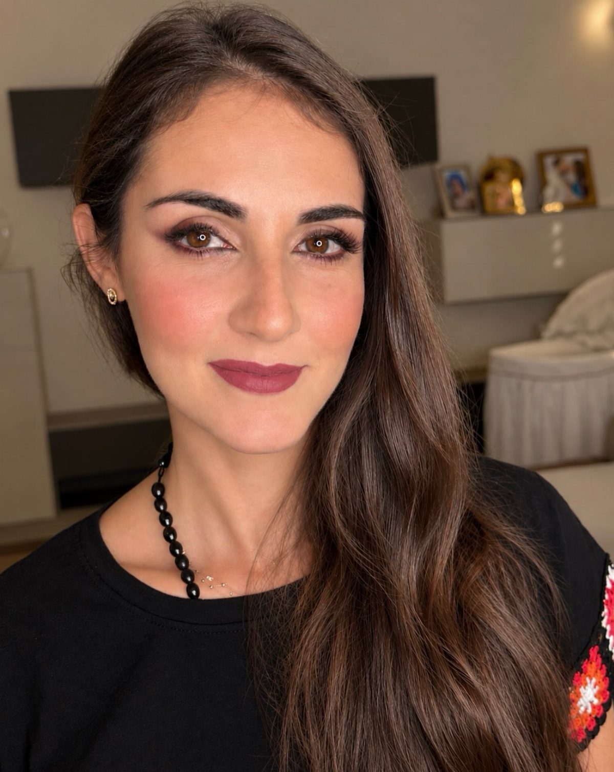 Woman with long brown hair wearing matte mauve-brown lipstick and neutral makeup.