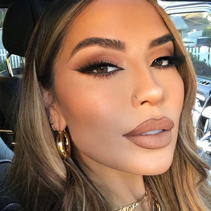 Woman with matte skin, winged eyeliner, and nude lips posing for a portrait.