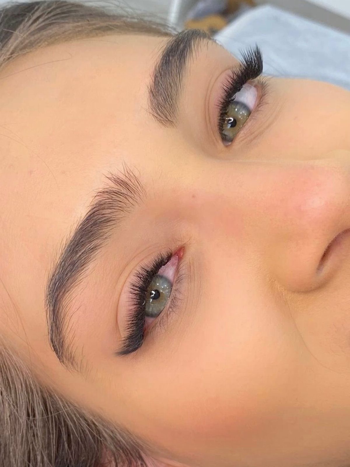 Close-up of eyes featuring long, thick, voluminous dark eyelashes and groomed eyebrows.