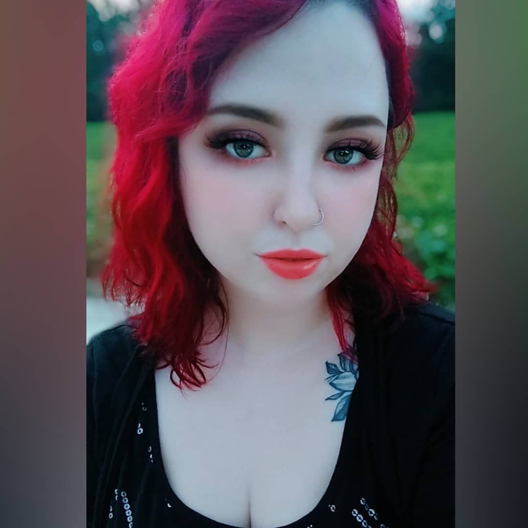 Woman with red hair and pale foundation wearing dark emo style makeup