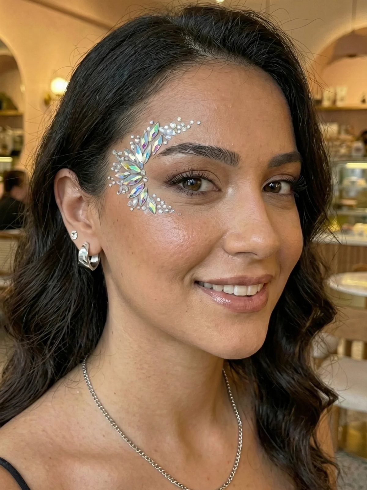 8 Eye Gem Ideas for Sparkly Party Makeup Looks 8 Woman with iridescent gems and rhinestones applied around her right eye as makeup.