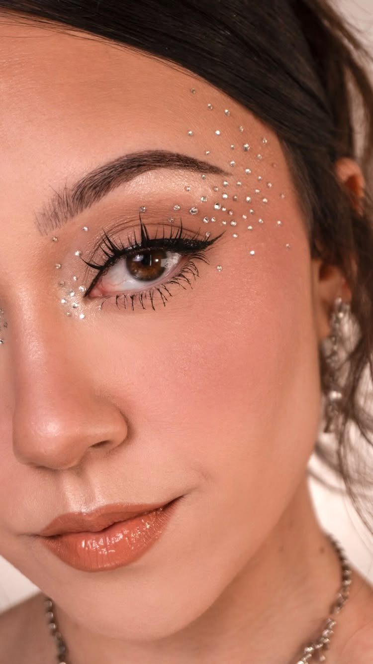 8 Eye Gem Ideas for Sparkly Party Makeup Looks 3 Person with clusters of clear rhinestones applied around their eye and temple.