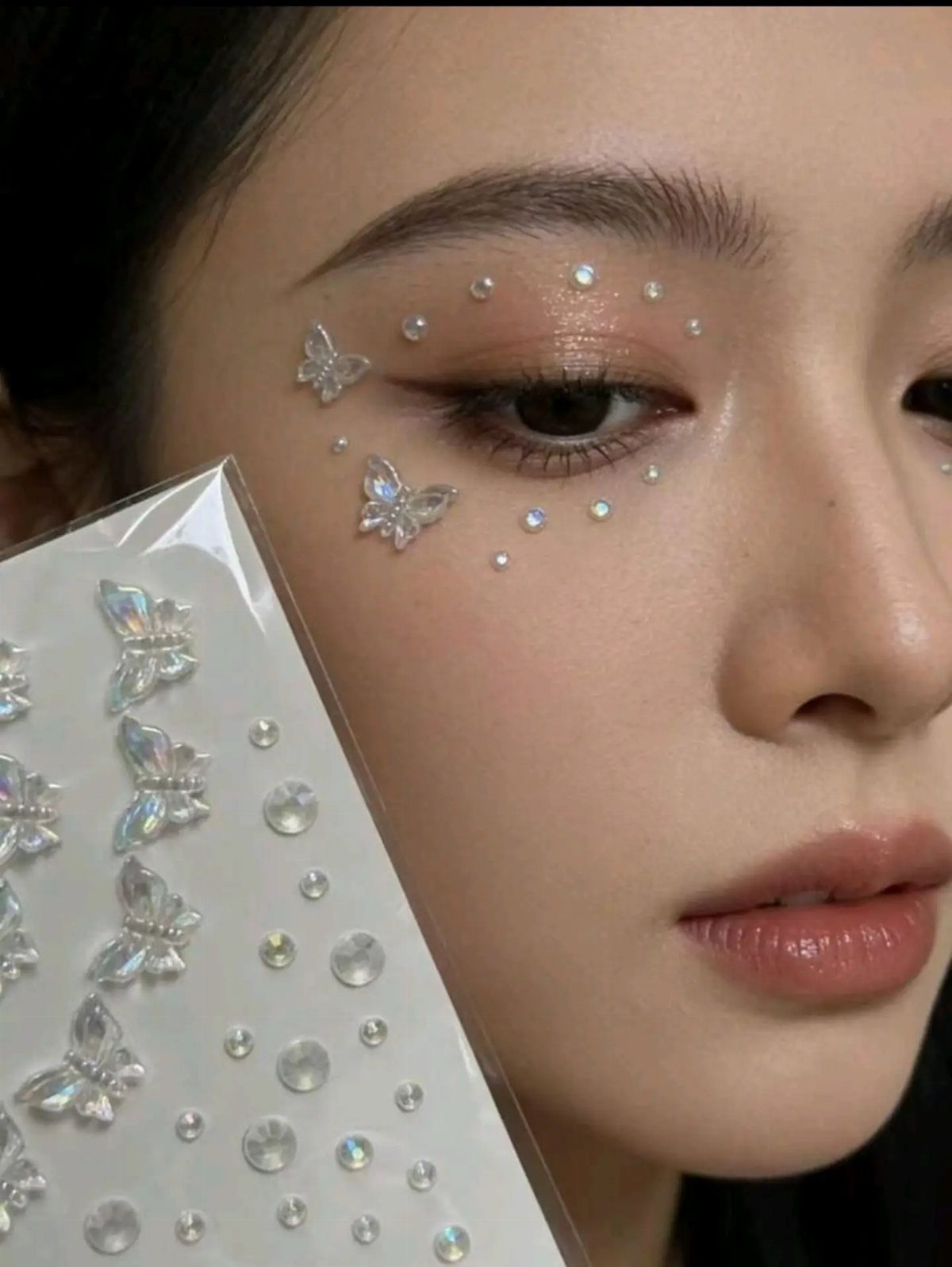 8 Eye Gem Ideas for Sparkly Party Makeup Looks 4 Person with iridescent butterfly and round gems applied around their eye