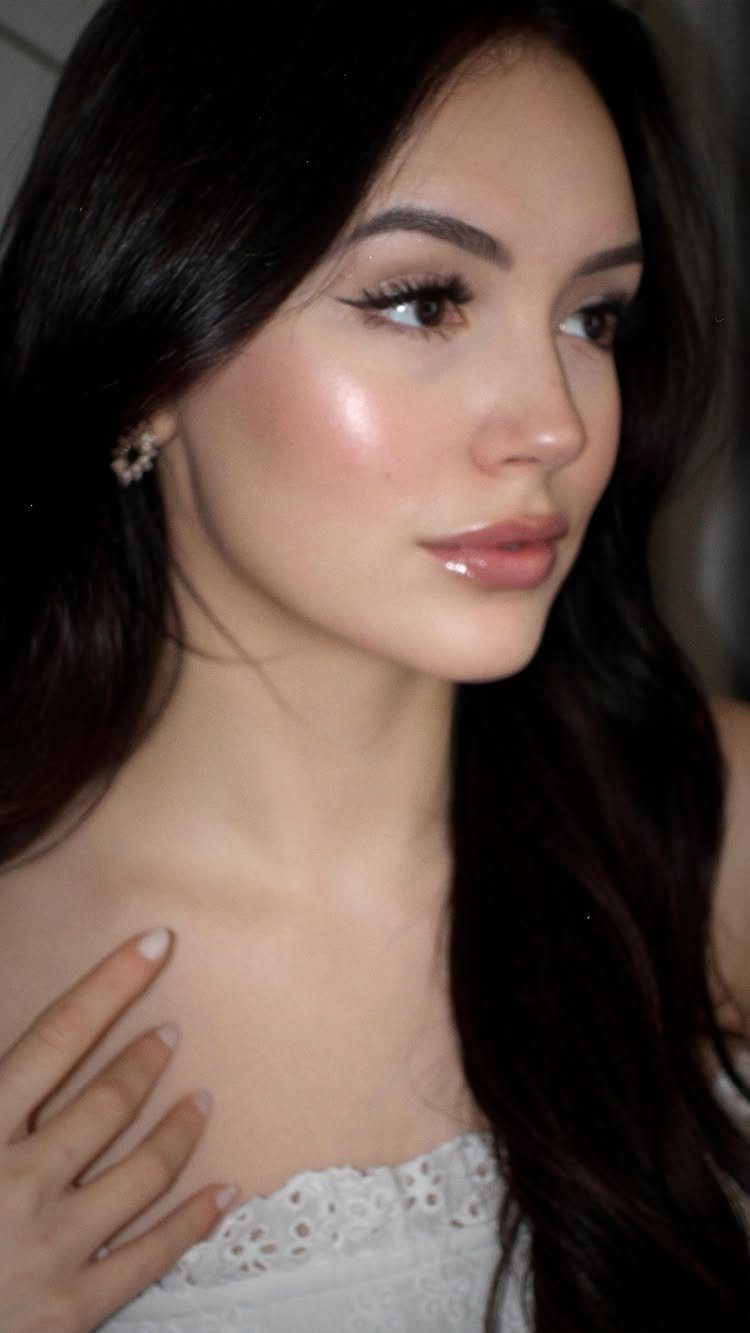 Woman with natural eye makeup, winged eyeliner, and glowing skin posing for a portrait.