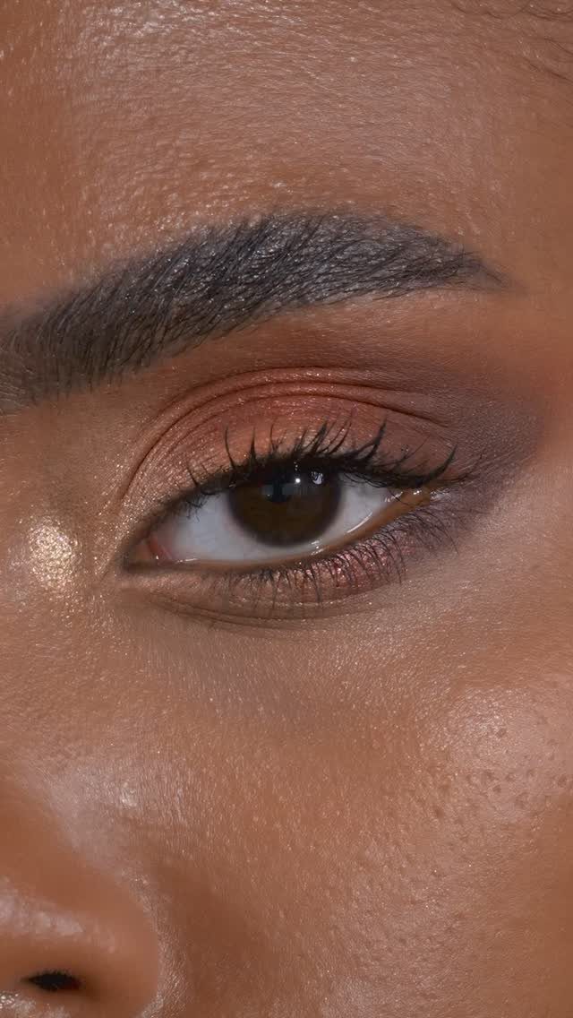 Eye with peach and terracotta eyeshadow, dark mascara, and a groomed eyebrow.