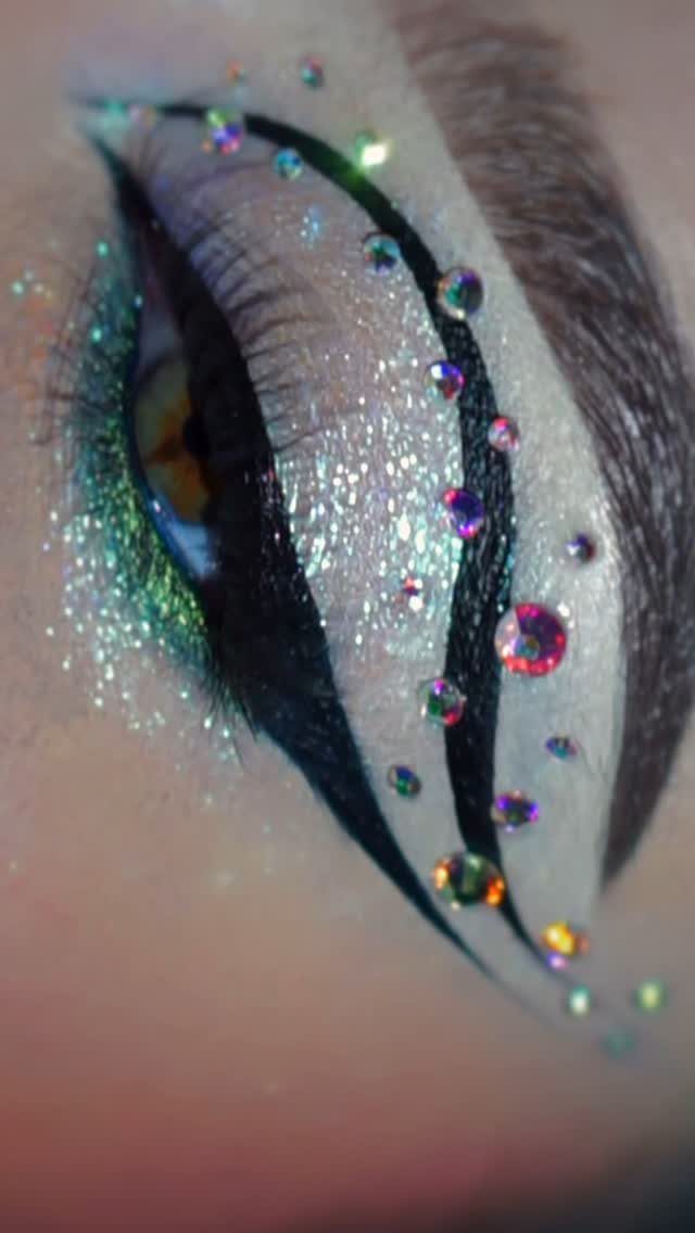 Eye makeup featuring floating black eyeliner, silver shimmer eyeshadow, and iridescent rhinestones.