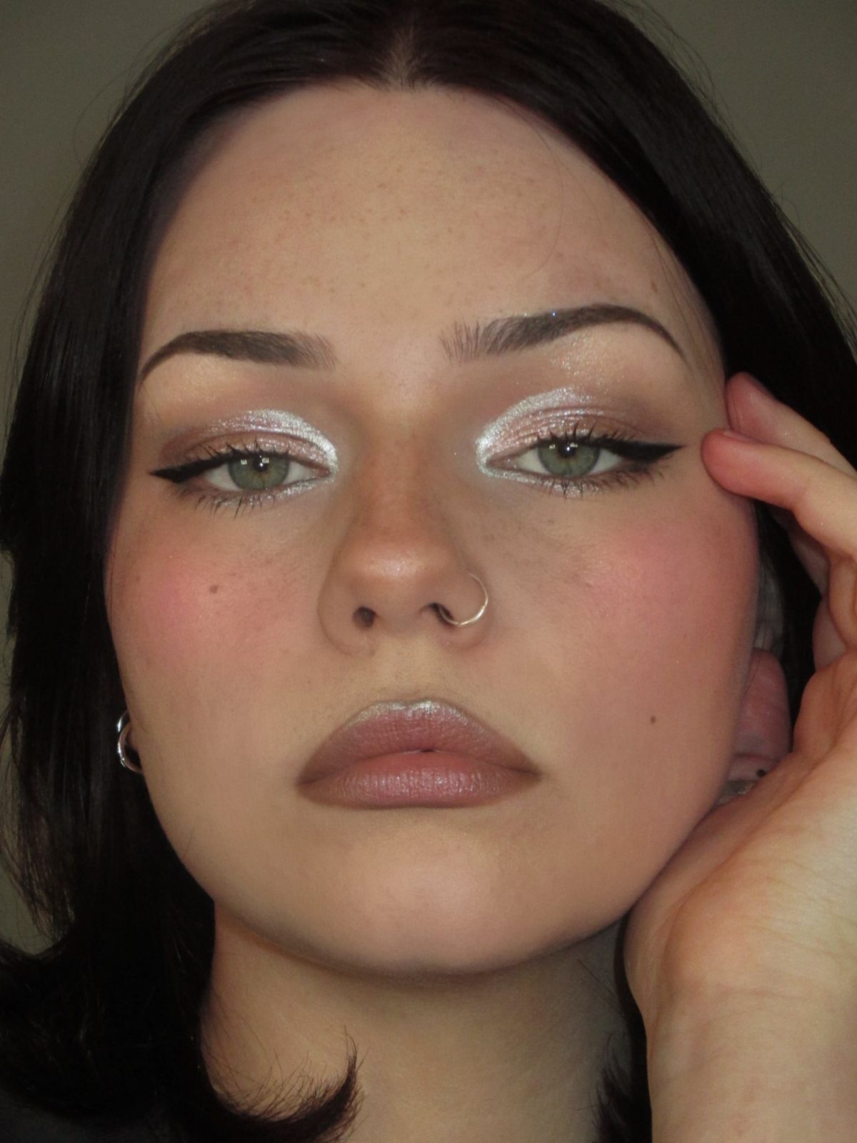 Woman with shimmering silver eyeshadow and black winged eyeliner looking at camera