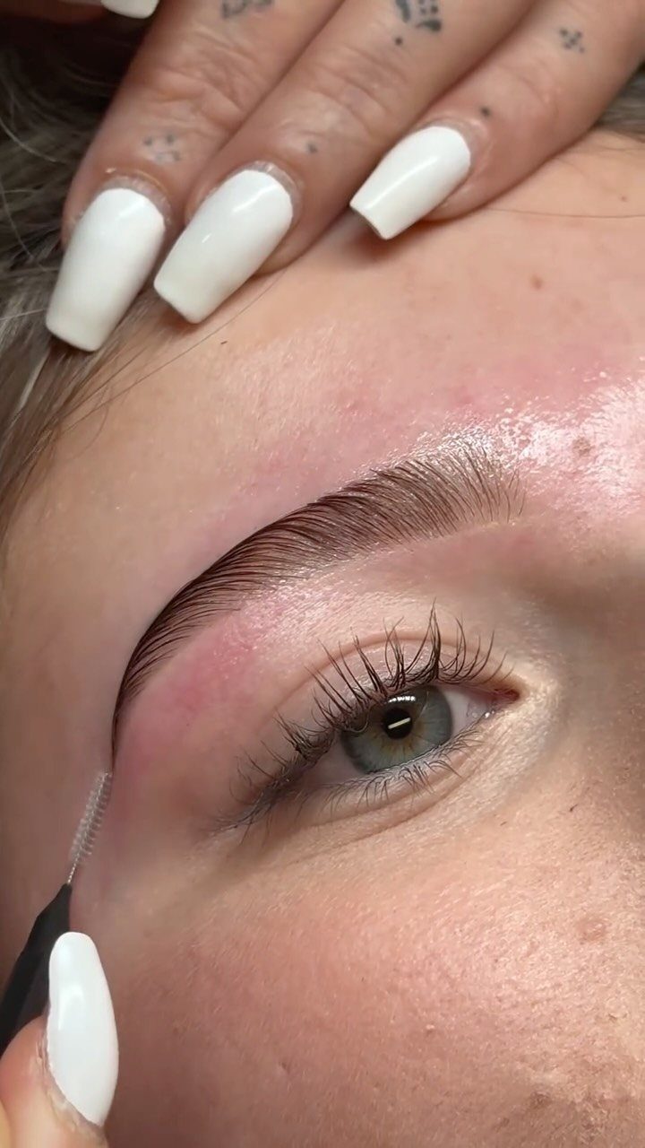 Close-up of a groomed eyebrow being shaped with a spoolie brush.