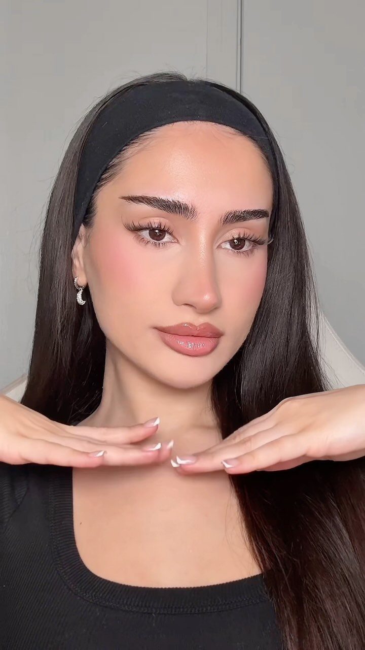 Woman with straight, groomed eyebrows, wearing a black headband and black top.