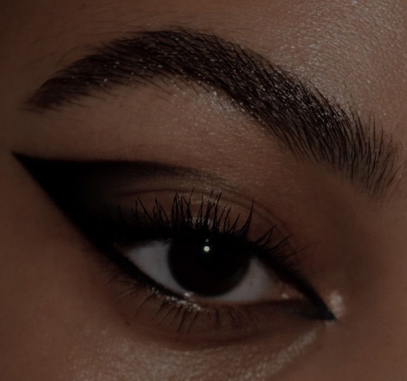 Eye with sharp black liquid eyeliner wing and dark smokey eyeshadow makeup.