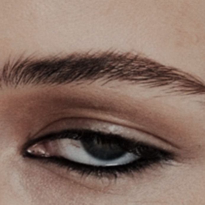 Close-up of an eye with dark smudged eyeliner and a groomed eyebrow.