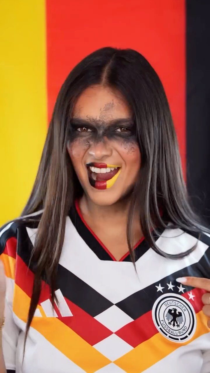 Woman in German football jersey with black eye paint and flag-colored lips.