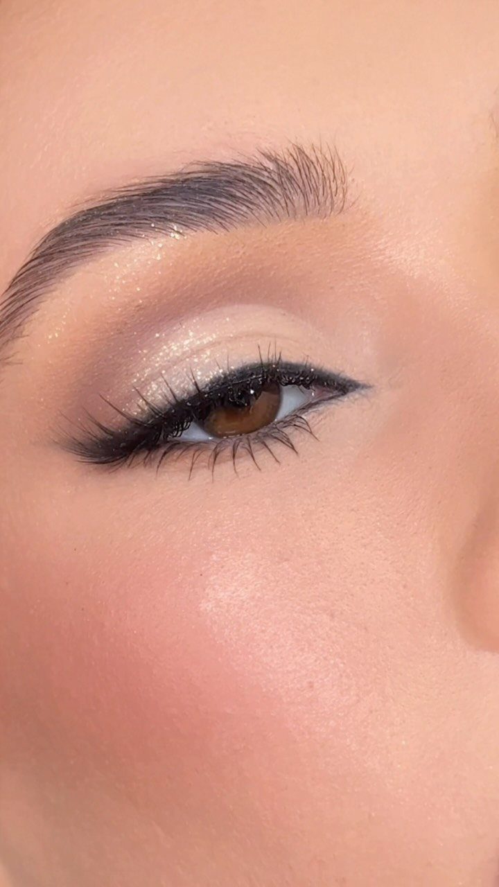 Close-up of an eye with gold glitter eyeshadow and winged black eyeliner.