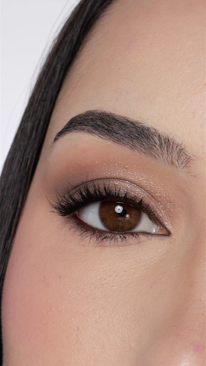 Close-up of a defined eyebrow and eye with shimmering neutral eyeshadow and mascara.
