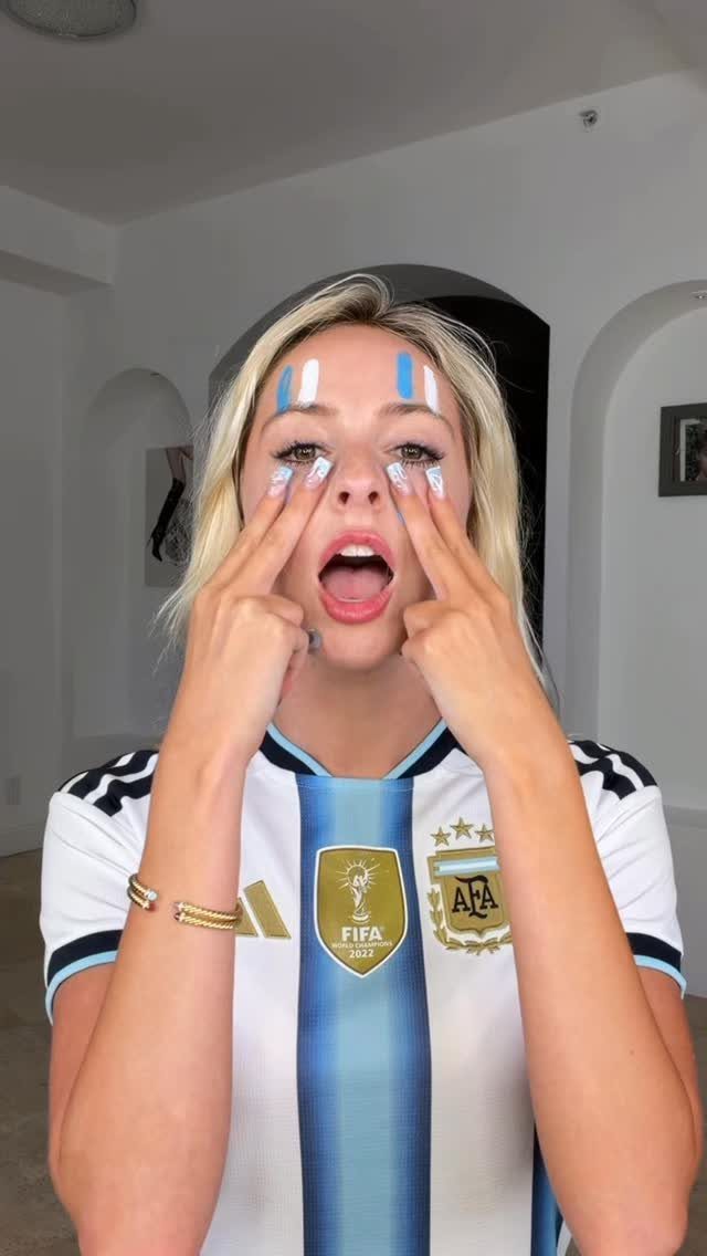 Woman in Argentina football jersey with blue and white face paint on cheeks
