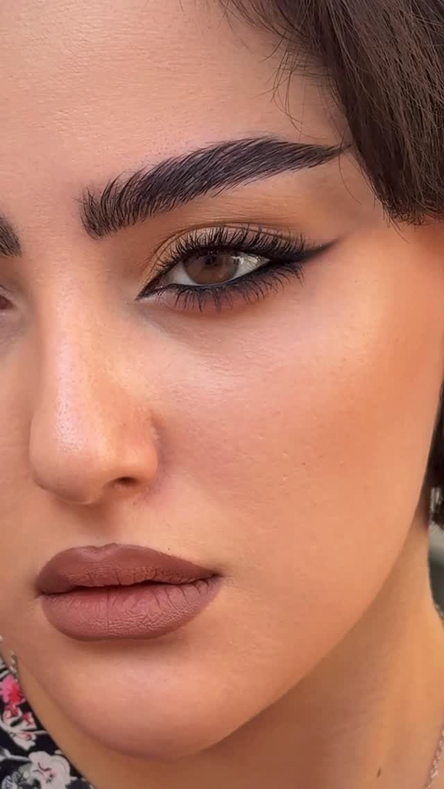 Woman with foxy eye makeup, winged eyeliner, and matte brown lipstick.