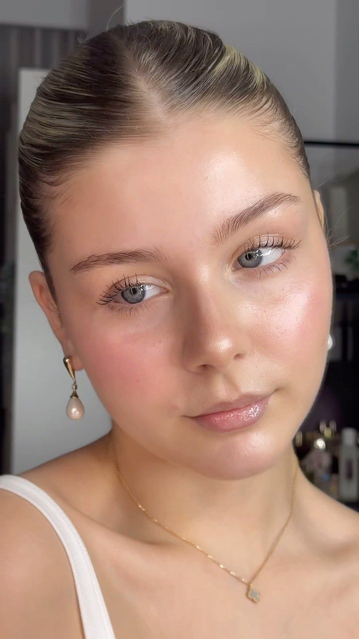 Woman with glowing, dewy glass skin and minimal makeup posing for a portrait.