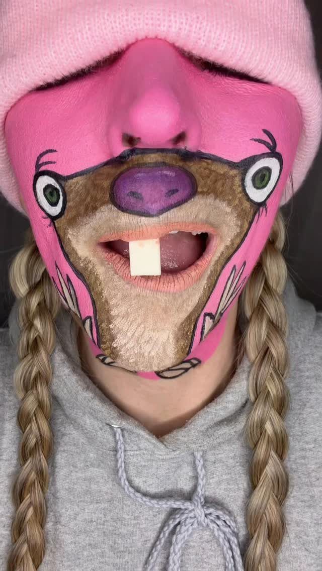 Person with pink and brown sloth face paint wearing a pink beanie.