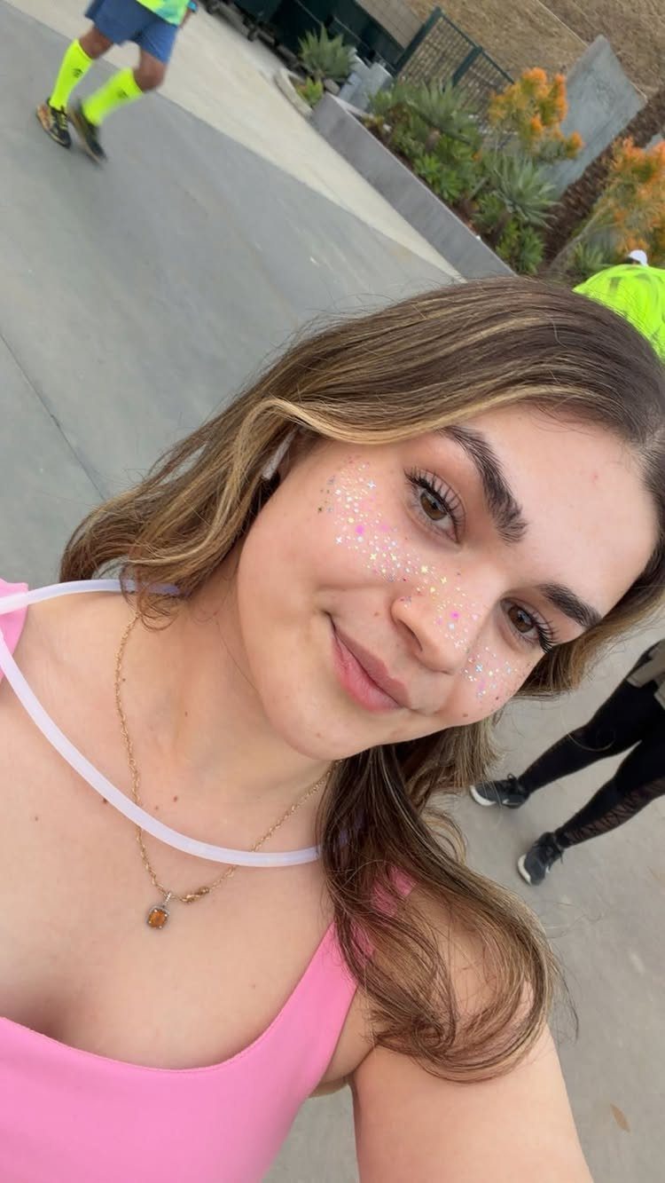 Glitter on Face Ideas: 19 Looks, From Freckles to Skulls 1 Young woman smiling with multicolored glitter freckles across her cheeks and nose.