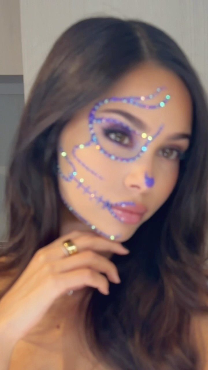 Glitter on Face Ideas: 19 Looks, From Freckles to Skulls 19 Woman with purple glitter makeup forming a skull design on her face