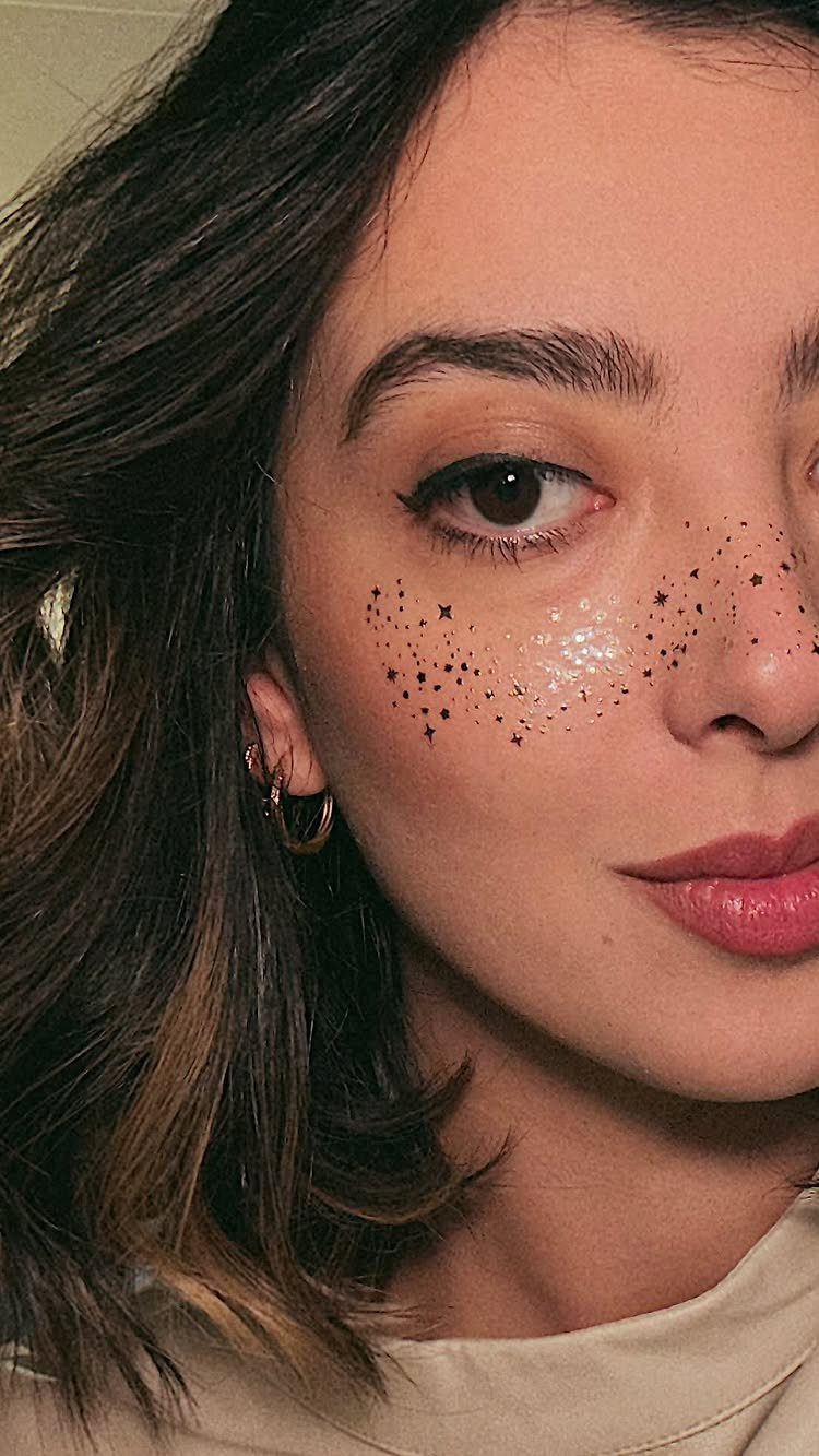Glitter on Face Ideas: 19 Looks, From Freckles to Skulls 15 Woman with black star glitter and silver shimmer on her cheek and nose