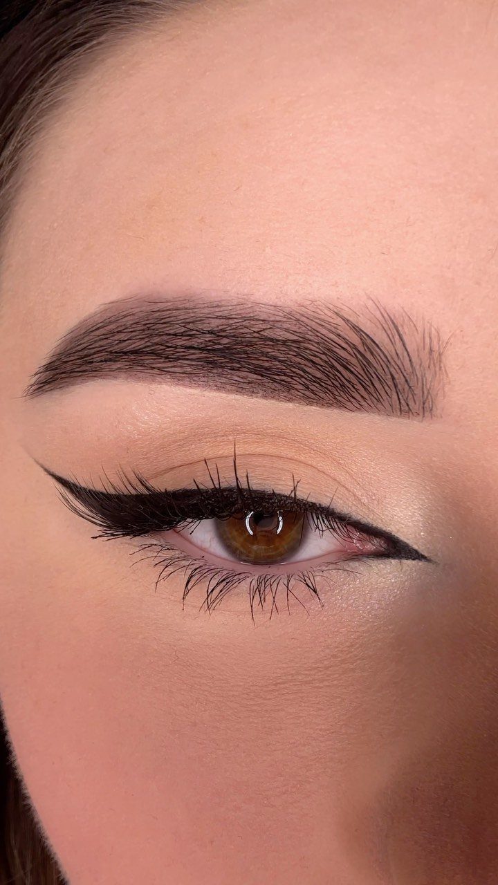 Close-up of an eye with sharp black winged eyeliner and groomed eyebrows.