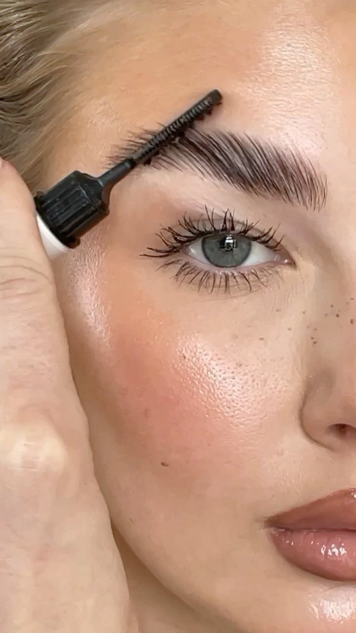 Woman's eyebrow being groomed with a black spoolie brush for a defined look.