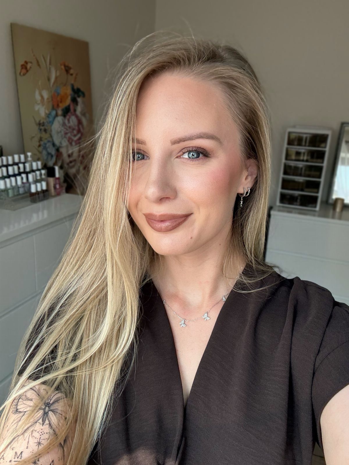 Woman with blonde hair and blue eyes wearing neutral makeup and black top