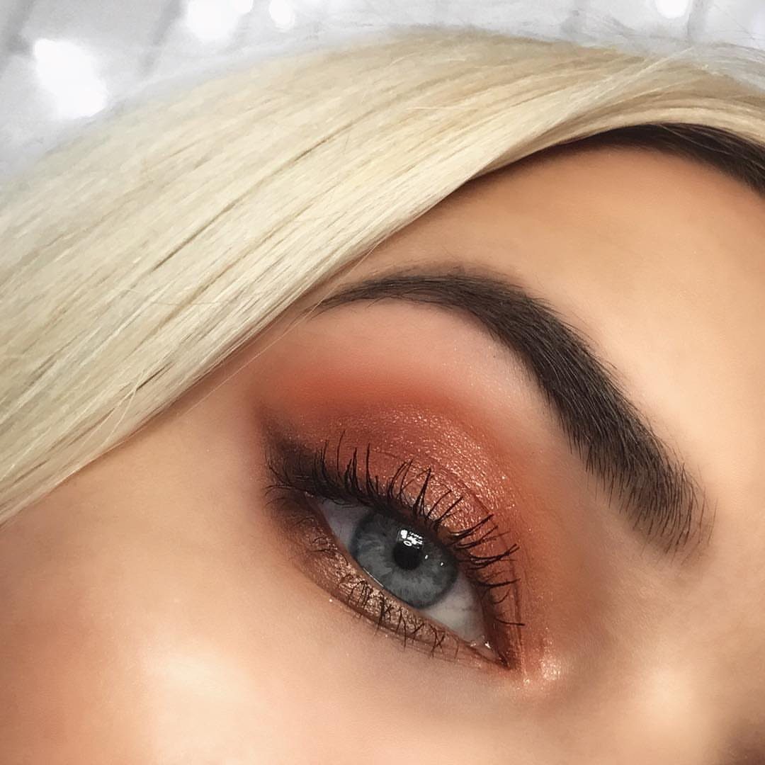 Blue eye with shimmering copper eyeshadow and a defined dark brown eyebrow.